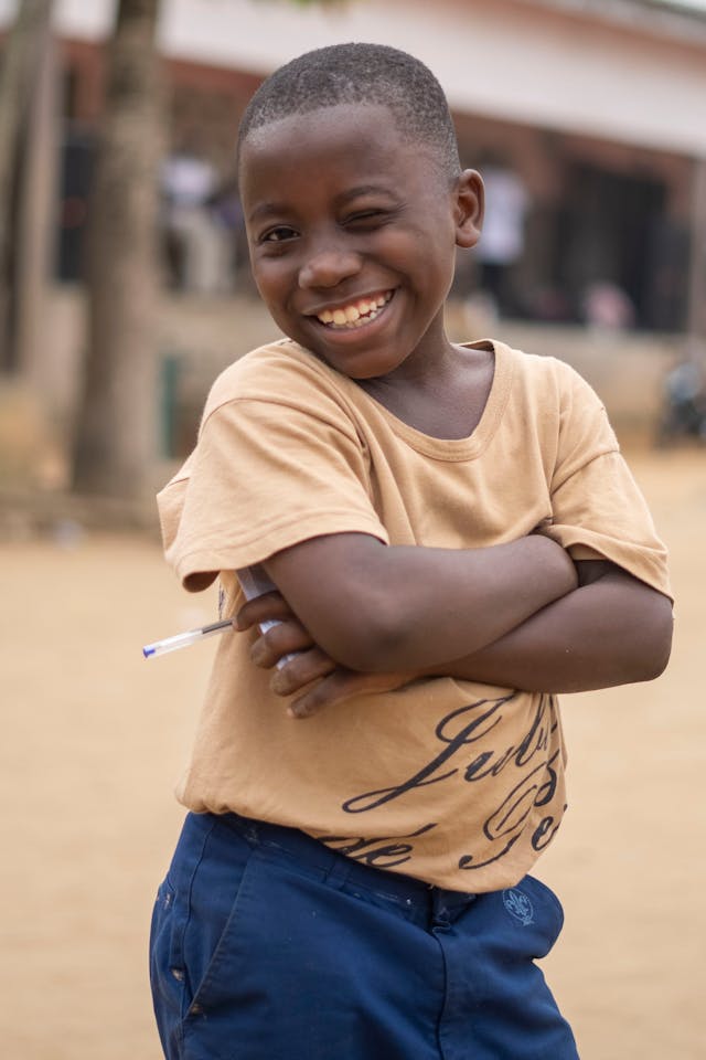 A young child stands outdoors in their community, dressed for the day ahead